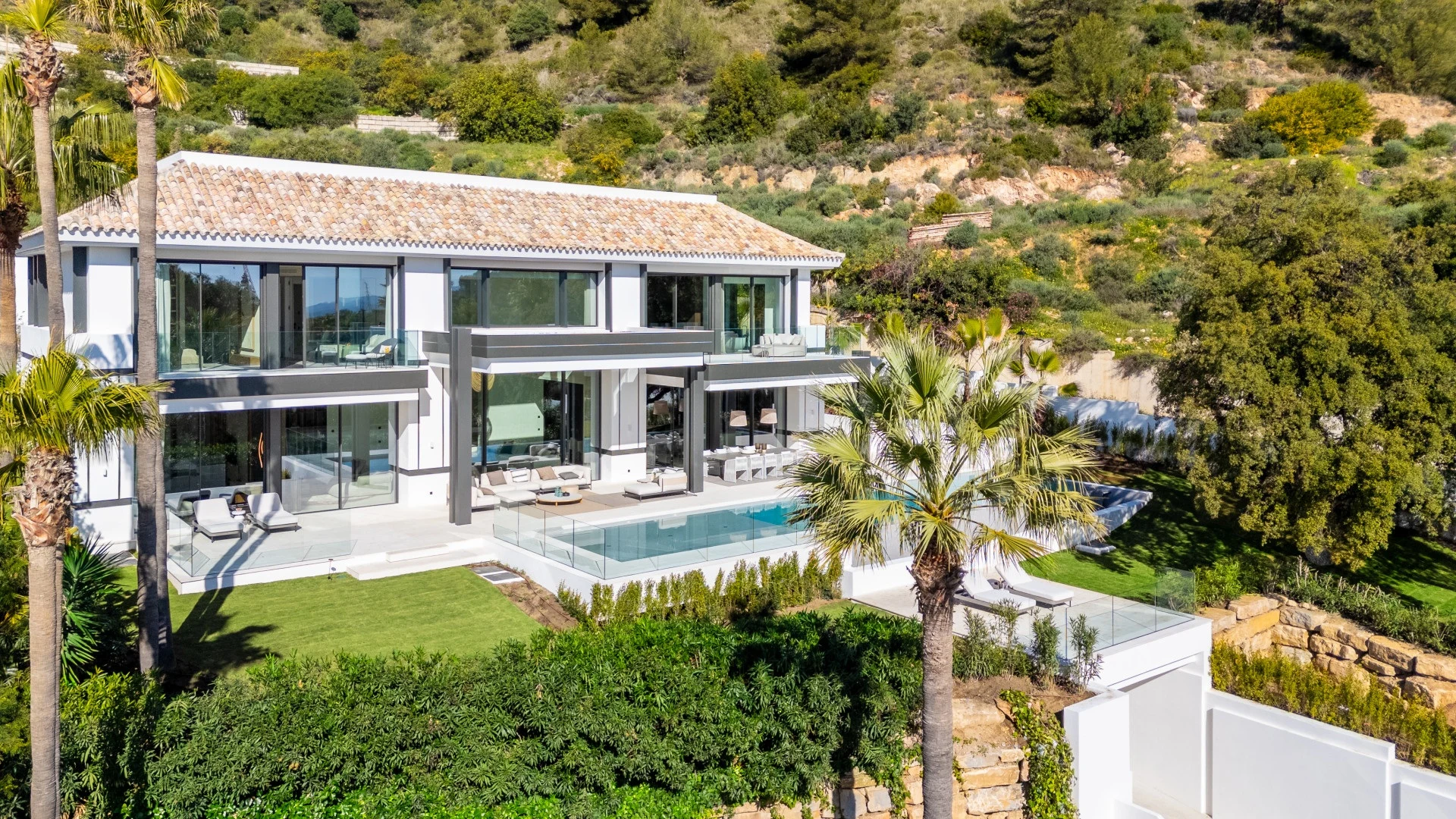 Villa exterior with landscaped gardens and pool in daylight