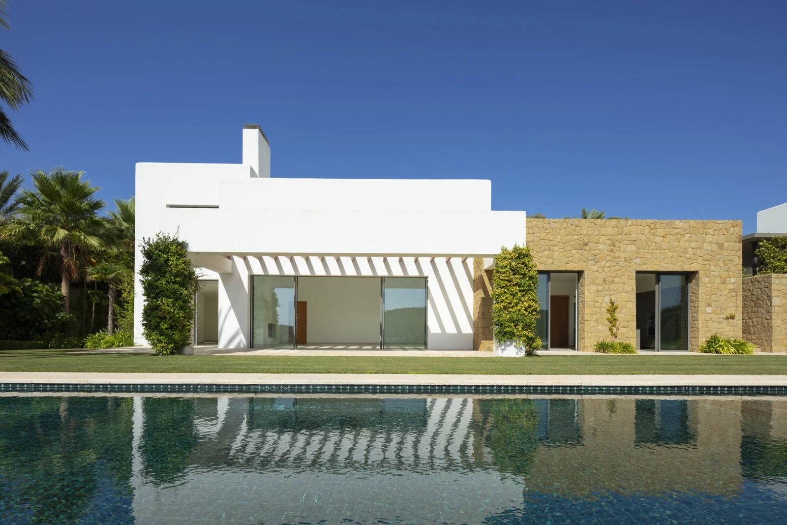 Pool-facing facade with white walls and natural stone