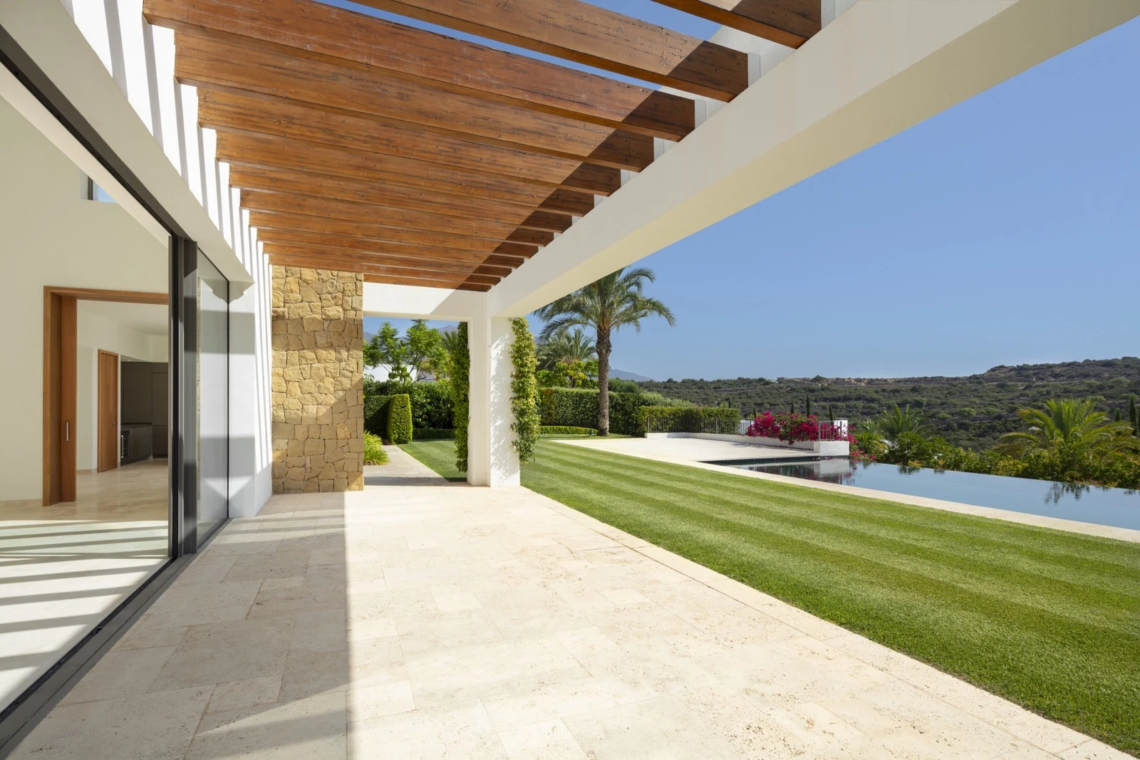 Covered terrace opening onto the lawn and pool