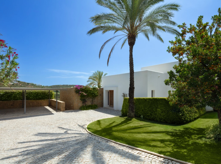 Private driveway and covered entrance beside mature palms