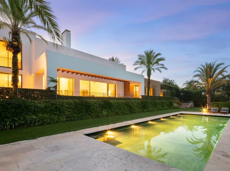 Illuminated private swimming pool and villa at dusk