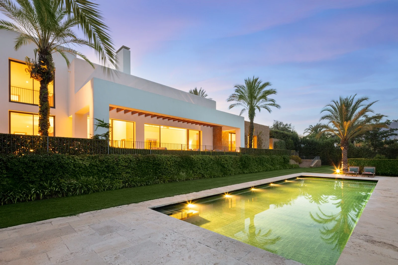 Illuminated private swimming pool and villa at dusk