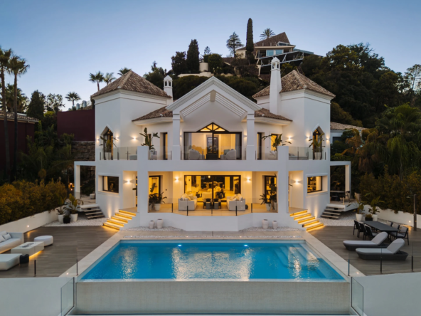 Five-bedroom villa with illuminated terraces and infinity pool at dusk