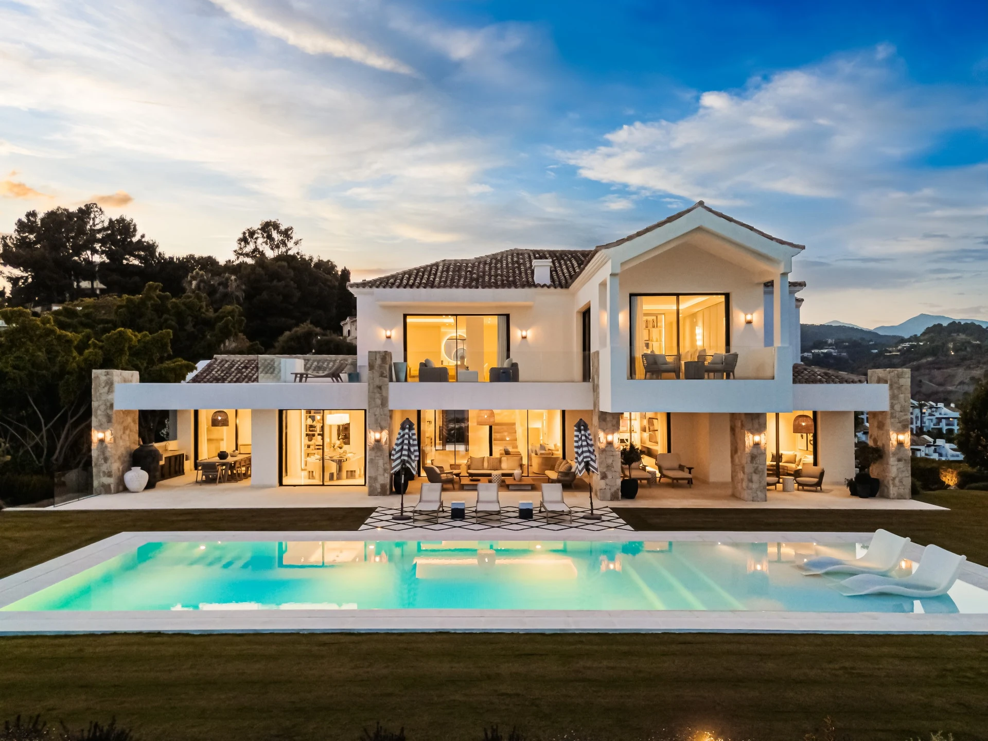 Eight-bedroom villa with illuminated terraces and private pool at dusk