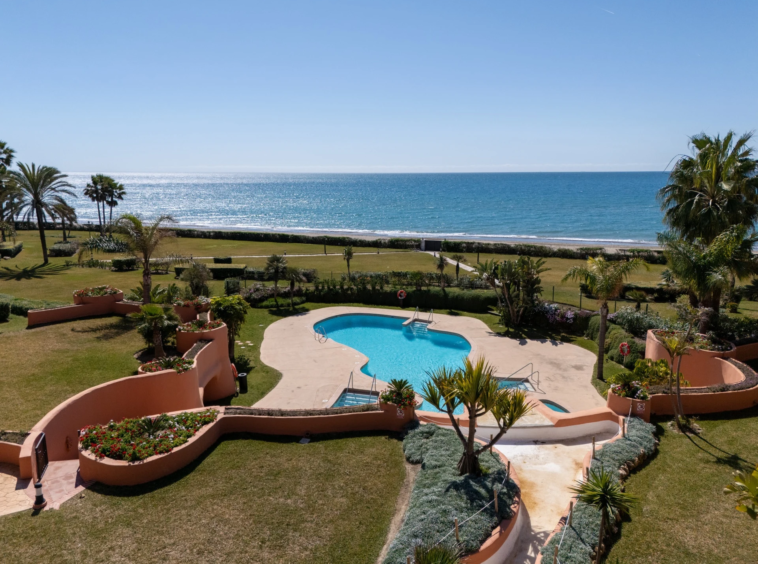 Sea view across the communal swimming pool and landscaped gardens