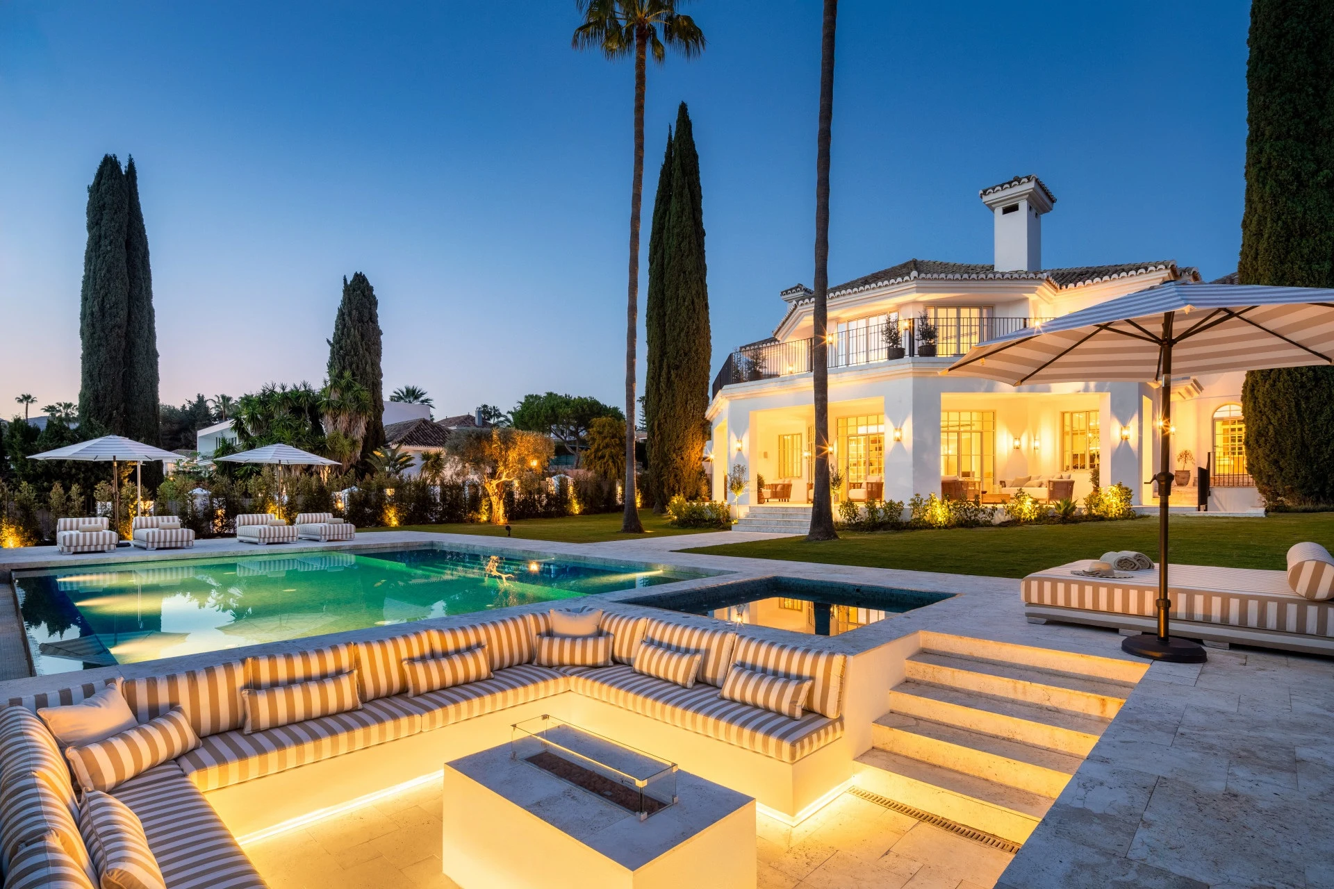 Illuminated sunken lounge and villa beside the pool at dusk