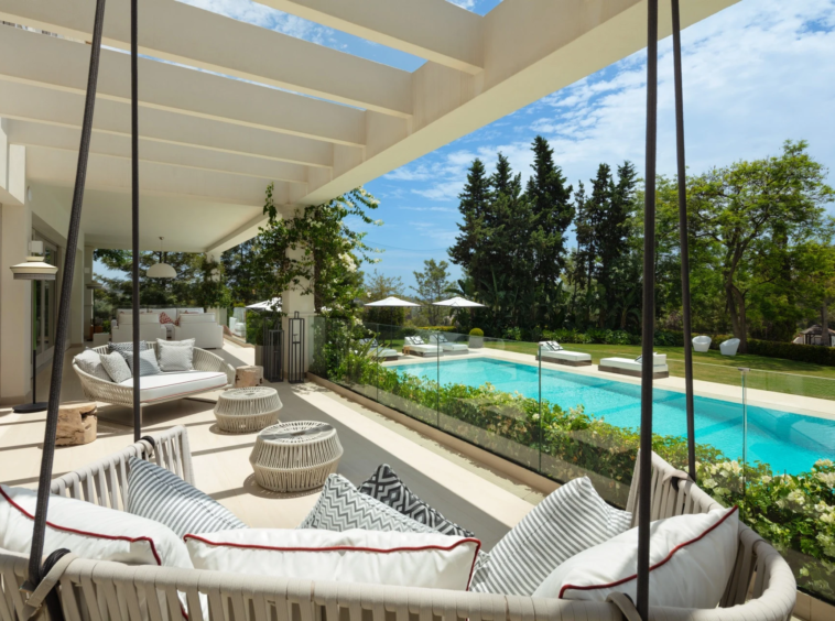 Covered terrace with hanging chairs overlooking the pool