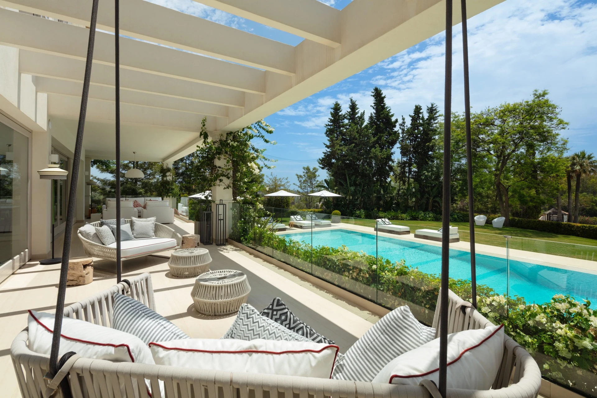 Covered terrace with hanging chairs overlooking the pool