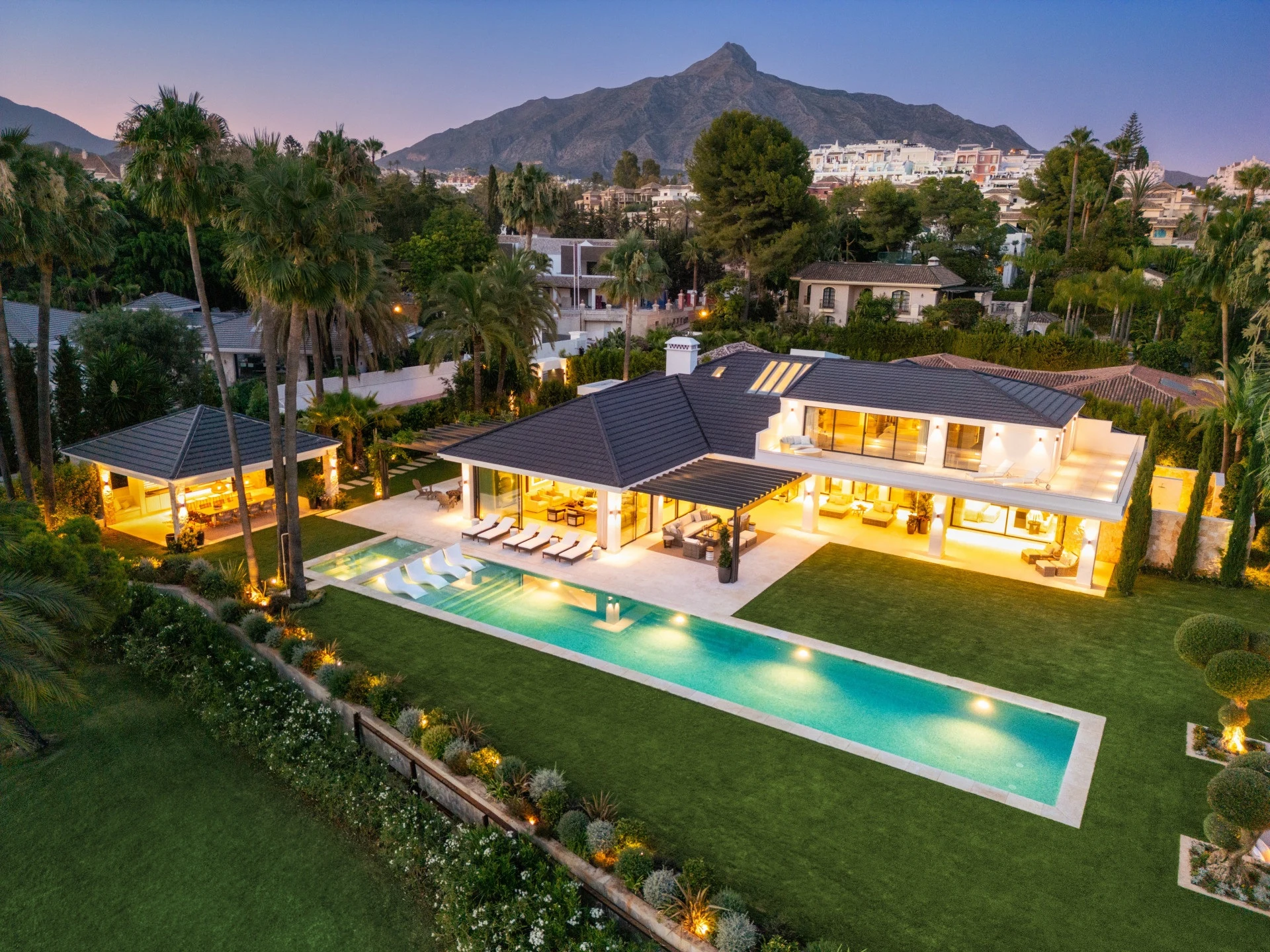 Seven-bedroom golfside villa with illuminated pool and garden at dusk