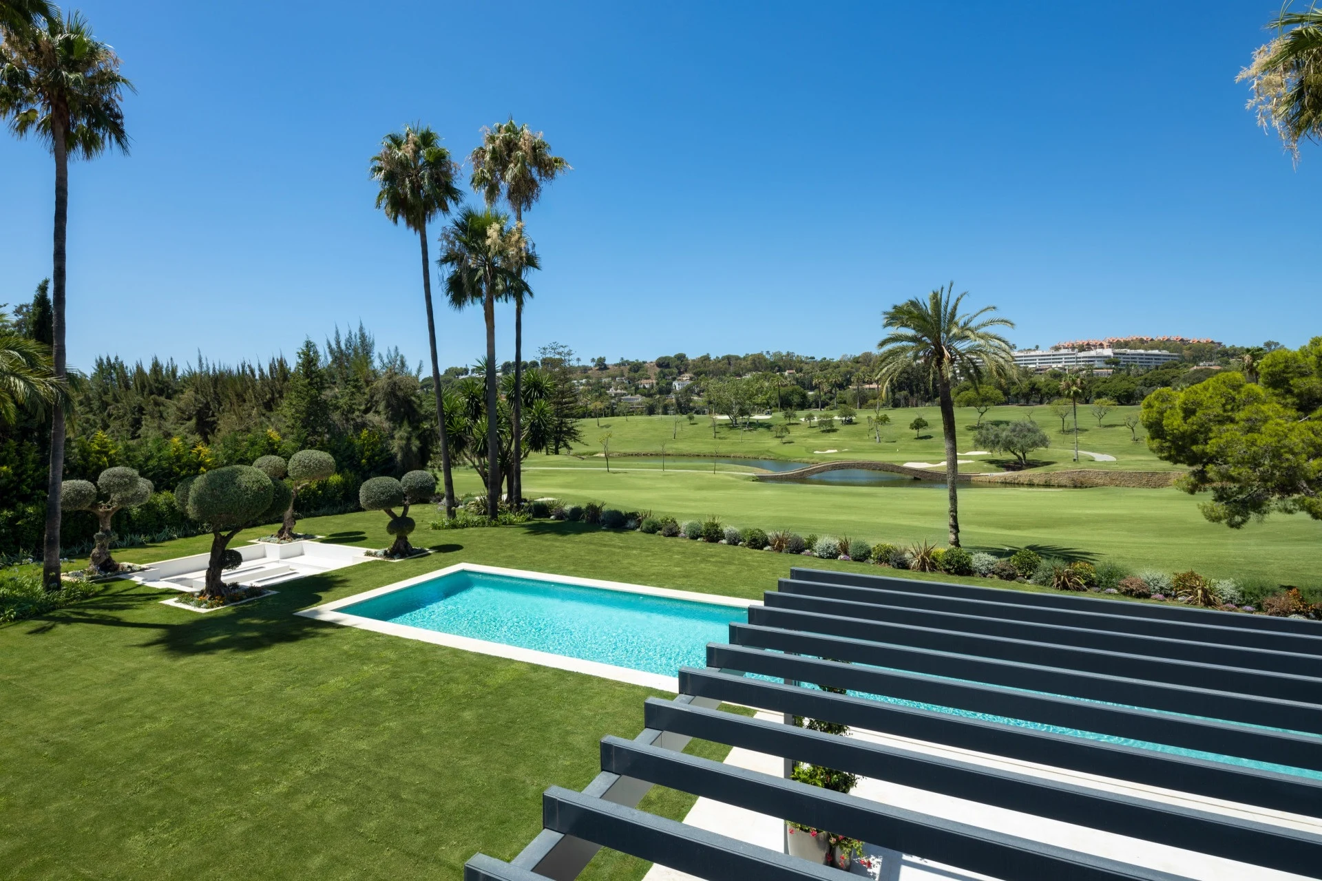 Upper terrace view over the private pool and neighbouring golf course