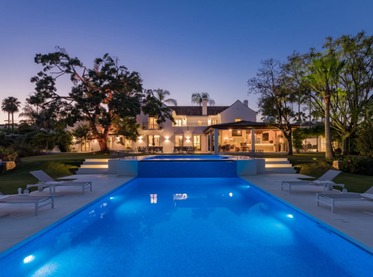 Illuminated swimming pool and garden at dusk