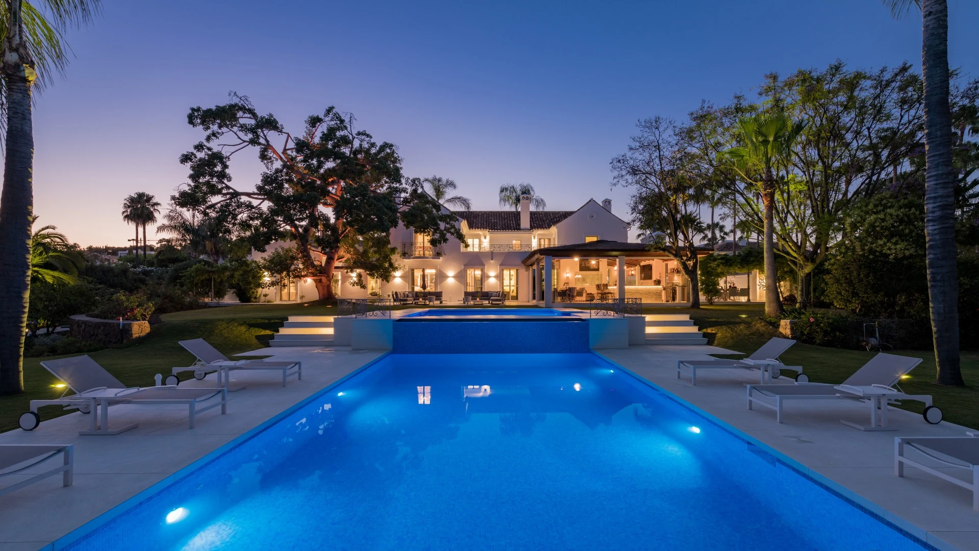 Illuminated swimming pool and garden at dusk