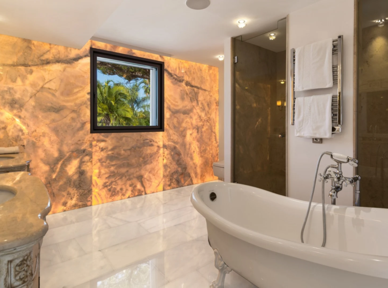 Bathroom with freestanding bathtub and illuminated stone wall