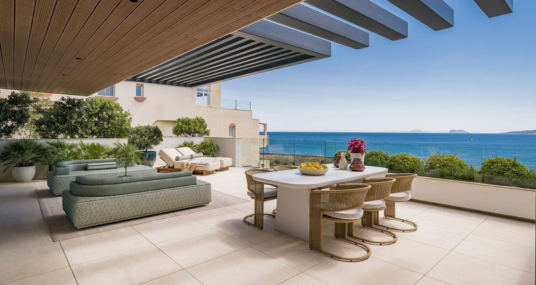 Beachfront apartment terrace with shaded dining and Mediterranean views