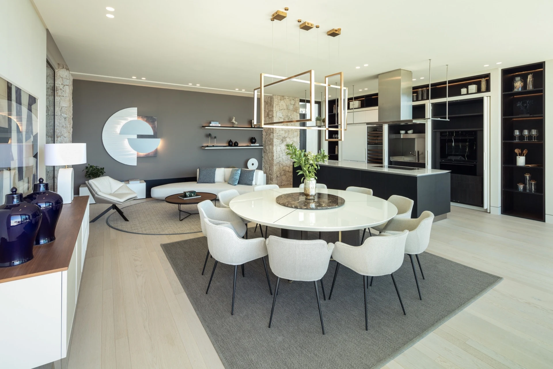 Round dining table beside the open kitchen and fitted display shelves
